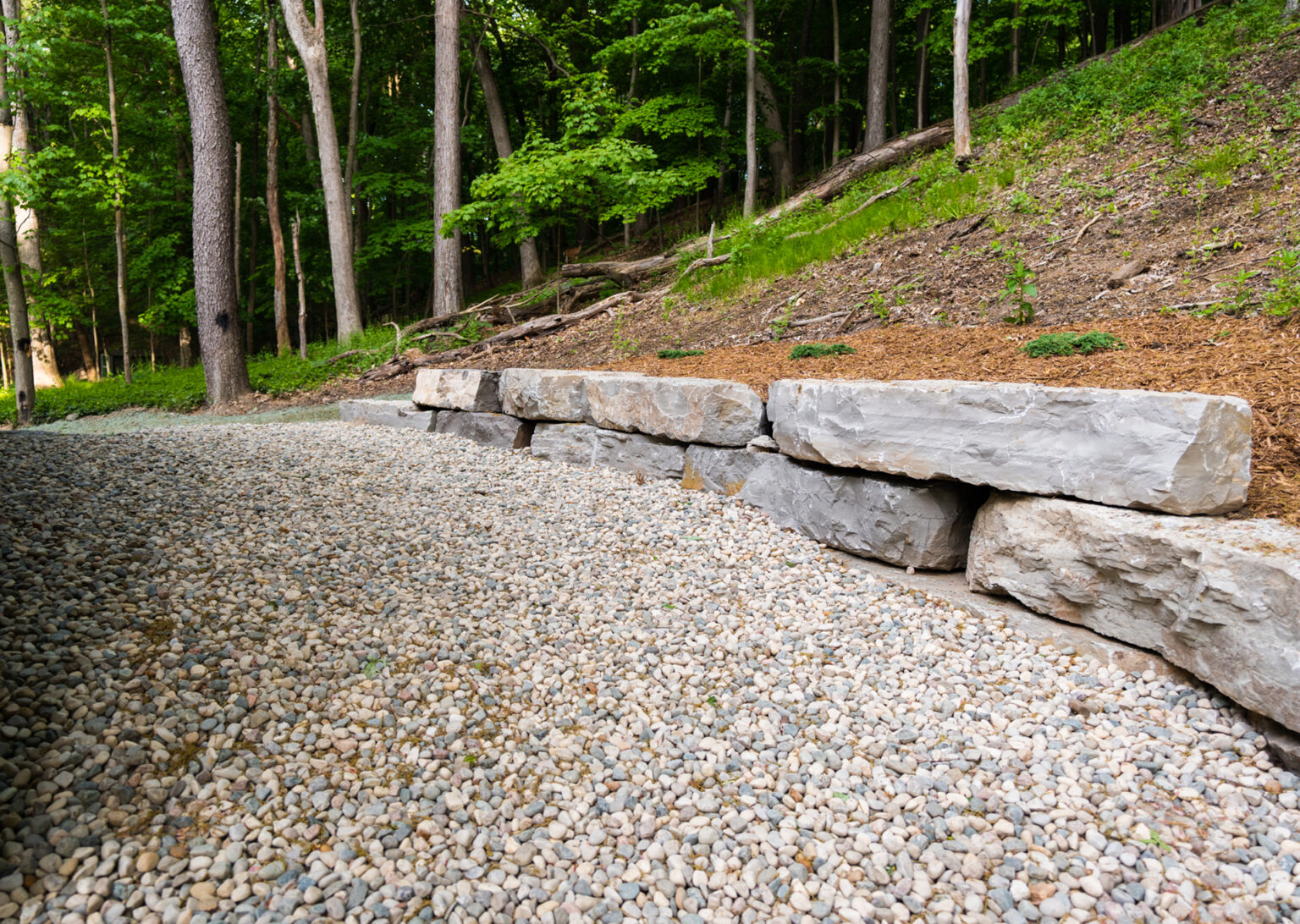 A natural drainage system with pea stones, large stones, and boulders.